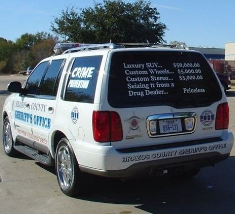 A logo on the back of a police SUV lists the price of the SUV and some customizations and concludes with the statement, 